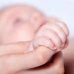 newborn baby clutching mother's finger